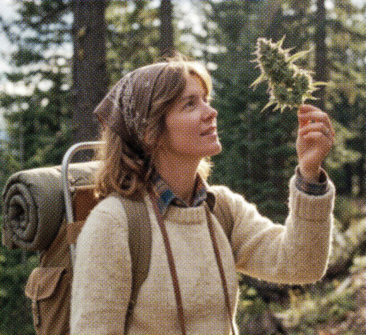 Hiker holding up a cannabis bud on the trail